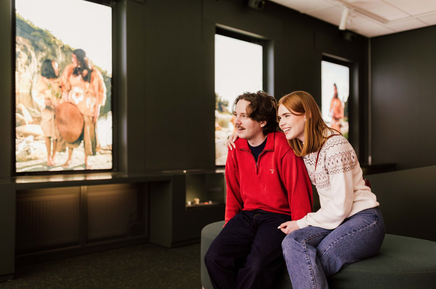 Nuoret nainen ja mies istuvat penkillä museon näyttelysalissa.